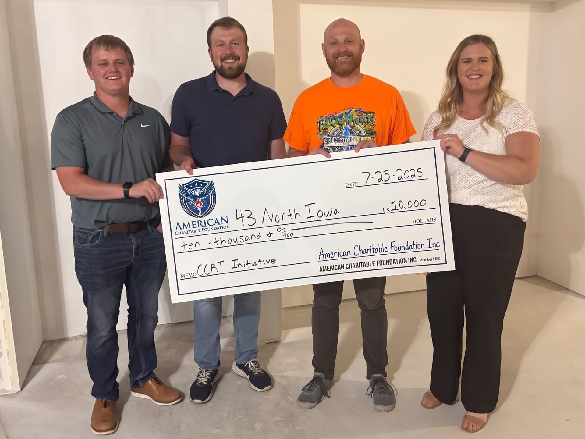 Four people presenting a large ACF grant check for 43 North Iowa in a newly constructed room