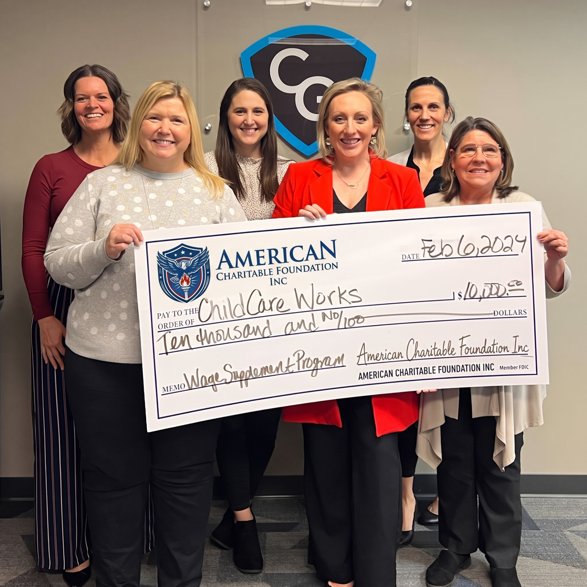 Six people holding an American Charitable Foundation check for $10,000 to Child Care Works for its Wage Supplement Program, dated February 6, 2024